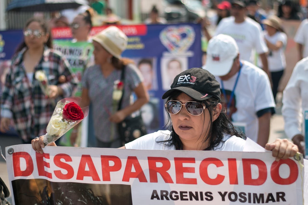 Demonstrators in Mexico rally for missing people, holding banners and red roses.